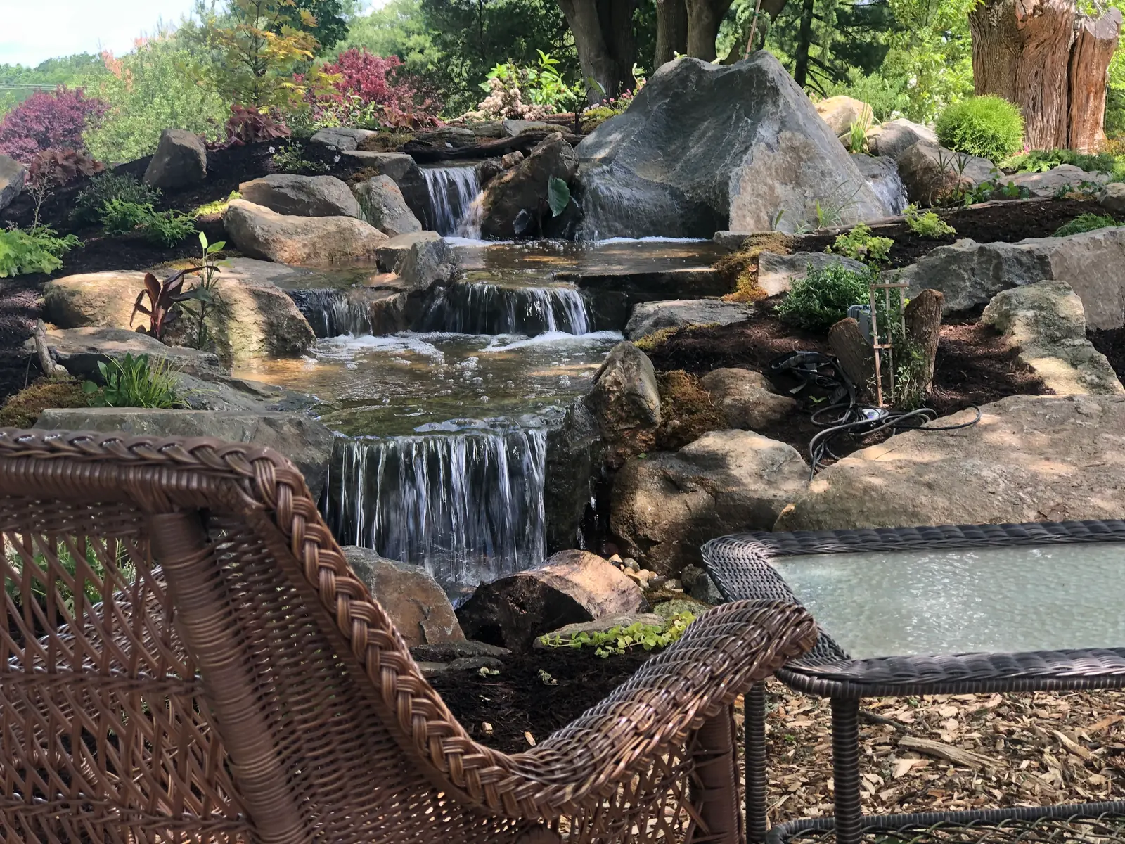 Completed multi-tier waterfall surrounded by natural boulders and mature landscaping