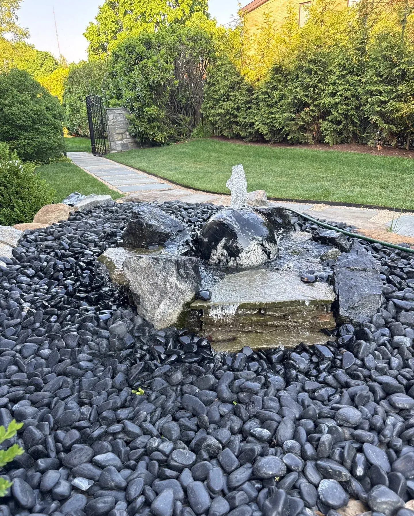 Compact fountainscape with natural stone, dark river rock, and a bubbling water feature