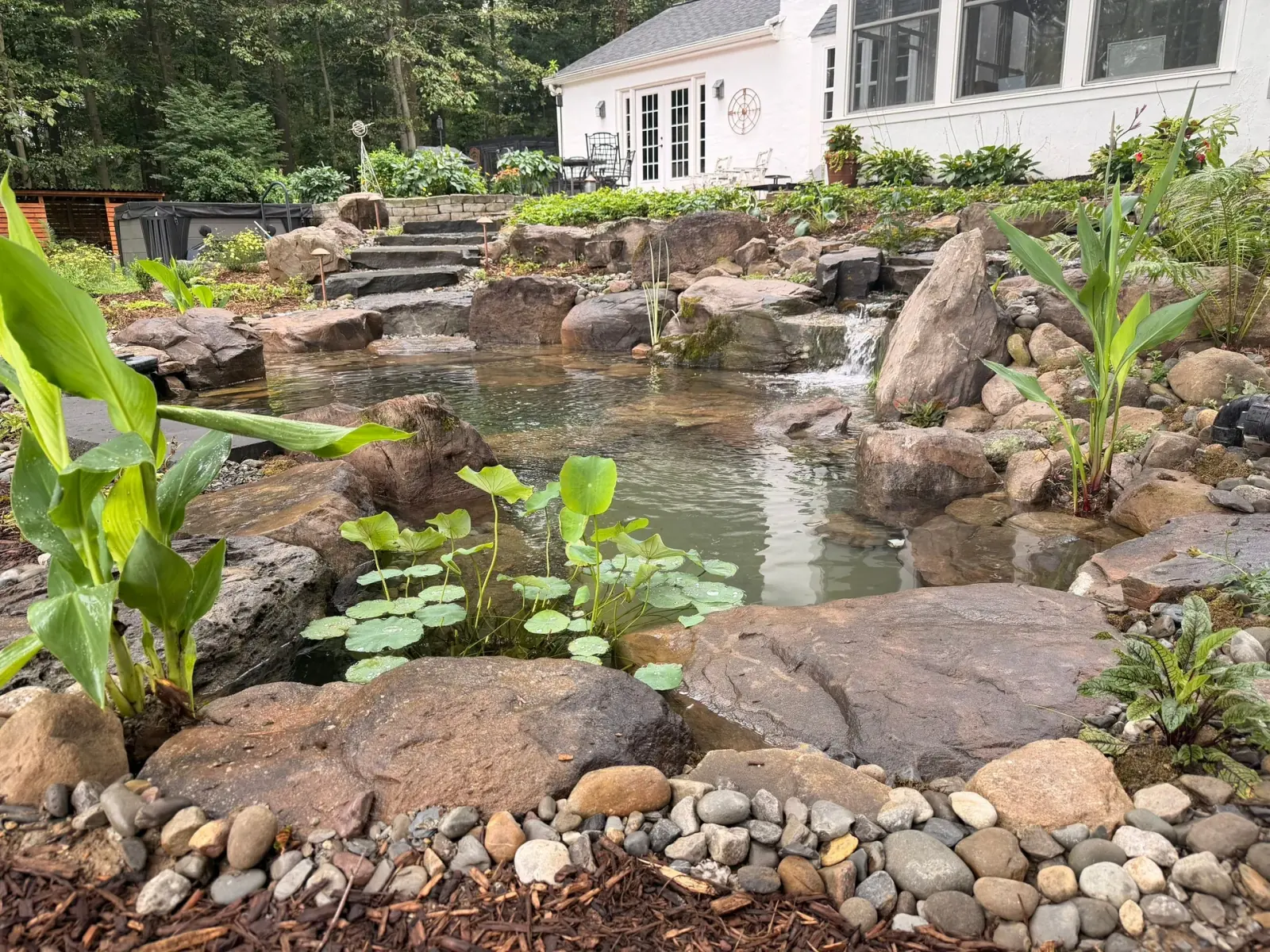 Natural swim pond with stone terraces, clear water, and a planted shoreline