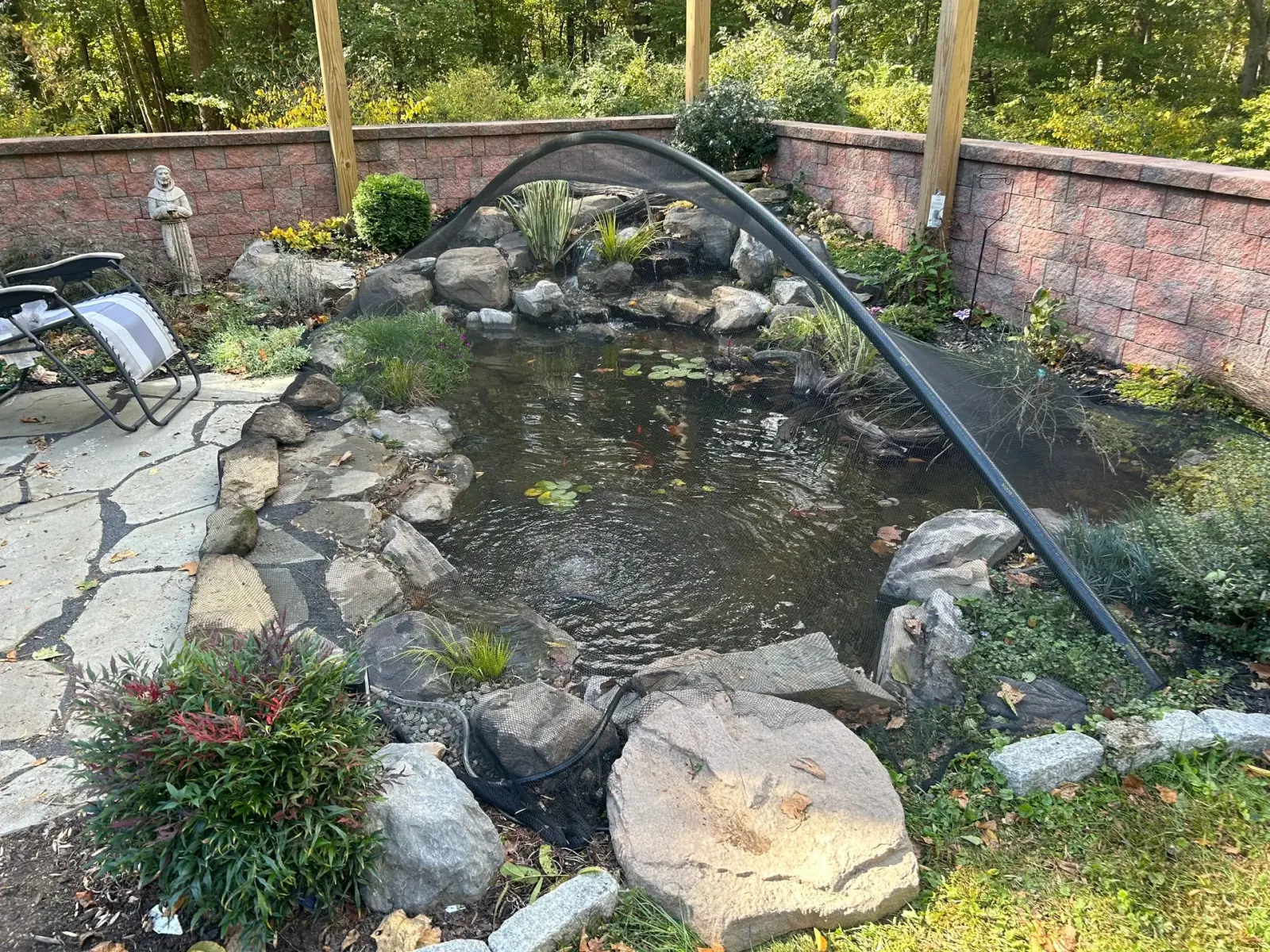 Custom dome netting installed over a landscaped backyard pond