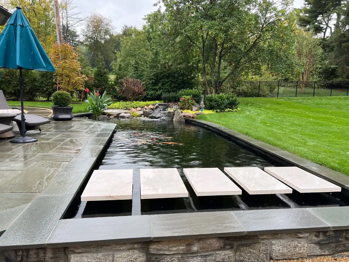 Finished backyard koi pond with clear water, stepping stones, and a waterfall